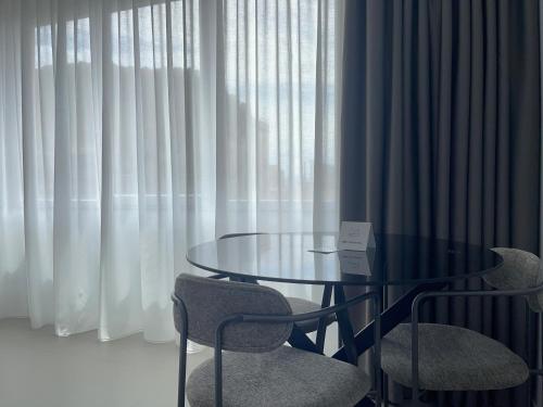 a glass table and two chairs and a table and curtains at OMÍ Aparthotel in Caserta