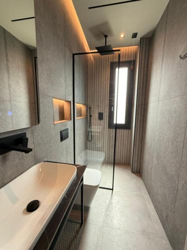 a bathroom with a tub and a toilet and a shower at South Inn Hotel in Vlorë