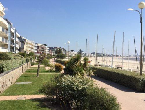 un trottoir avec des buissons, une plage et des bâtiments dans l'établissement Résidence baie de la baule, à La Baule