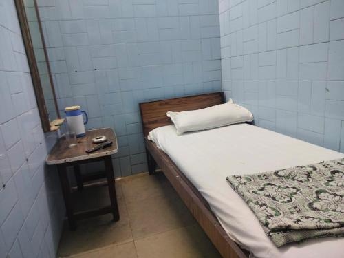 a small room with a bed and a table with a mirror at Milan Guest House in Mumbai