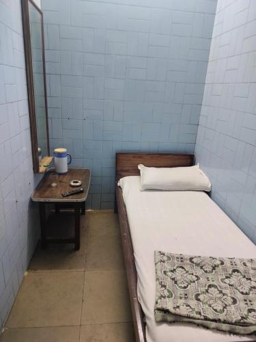a small room with a bed and a table with a mirror at Milan Guest House in Mumbai