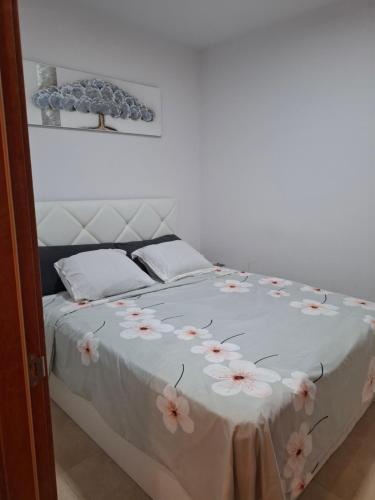 a white bed with pink flowers on it at Primi House in La Nucía