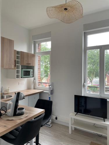 Il comprend une cuisine avec une table et une télévision. dans l'établissement Studio équipé à Valenciennes centre, à Valenciennes