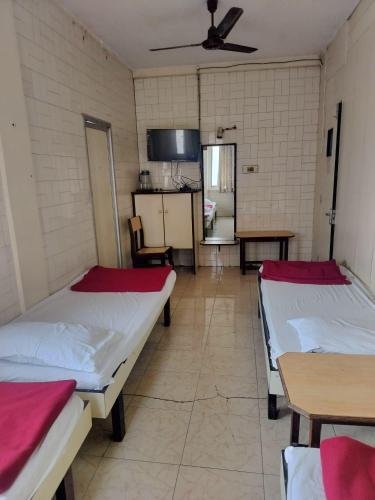a room with two beds and tables in it at Milan Guest House in Mumbai
