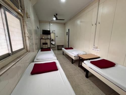 a hospital room with three beds and a window at Milan Guest House in Mumbai
