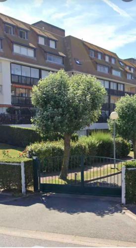 un arbre devant une clôture devant un bâtiment dans l'établissement Résidence Deauville 2000 à 50m plage, à Villers-sur-Mer