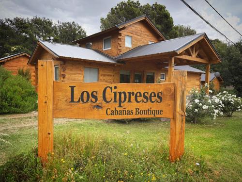 a wooden sign in front of a house at Cabañas Boutique Los Cipreses in Villa Ventana
