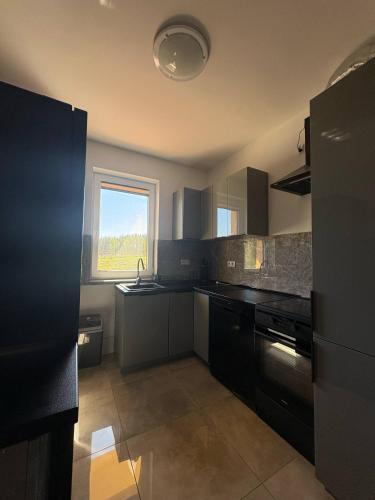 a large kitchen with black appliances and a window at Agroturystyka Żółta Ostoja in Lipowo