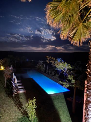 a swimming pool lit up at night at Kasbah Oum Rabia in Boulaouane