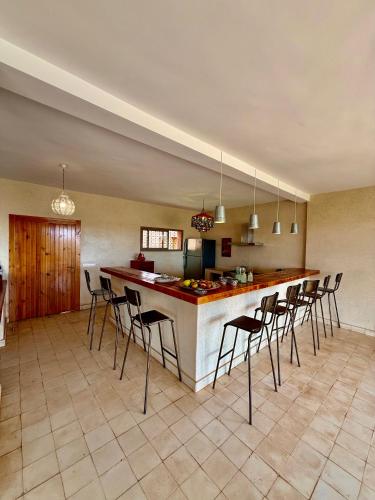 a kitchen with a bar with a bunch of stools at Kasbah Oum Rabia in Boulaouane