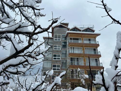 a tall building is covered in snow at The Ravasa in Manāli
