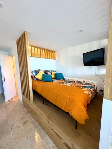 - une chambre avec un grand lit et une couette en orange dans l'établissement Dolce Vita, au Cap d'Agde