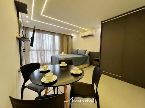 a room with a table and chairs and a bed at Vert House Jardim Oceania - Miramar Hospedagens in Tambaú