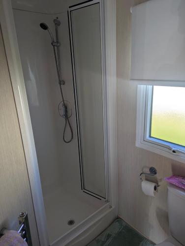 a shower in a bathroom with a toilet and a window at Abi Sunset - Camber Sands in Camber