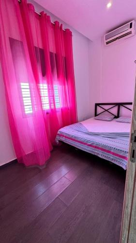 a room with pink curtains and two beds in it at Chacha house in Yasmine