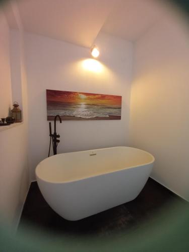 a white bath tub in a bathroom with a painting at La Piccola Corte da Anita in Tortolì