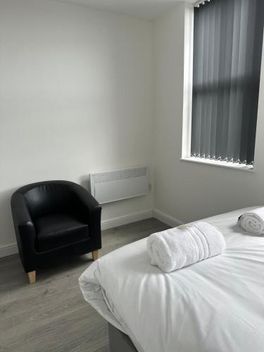 a bedroom with a bed and a black chair at Train Station Aparthotel - Free Wifi, Free Parking in Scunthorpe