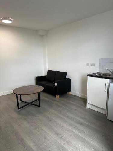 a living room with a black couch and a table at Train Station Aparthotel - Free Wifi, Free Parking in Scunthorpe