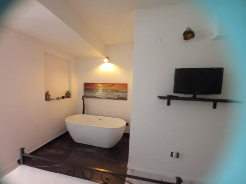 a bathroom with a bath tub and a tv at La Piccola Corte da Anita in Tortolì