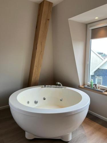 a white bath tub in a bathroom with a window at Luxury Spa with Sauna, Bath and Cinema Private in Bodegraven