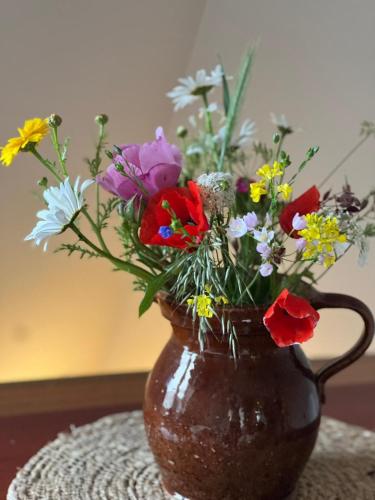 a brown vase filled with colorful flowers on a table at Luxury Spa with Sauna, Bath and Cinema Private in Bodegraven