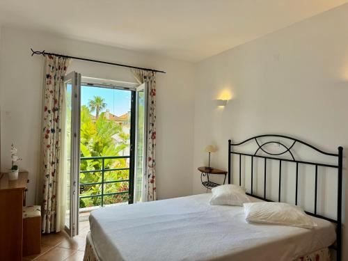 une chambre avec un lit et une porte donnant sur un balcon dans l'établissement Grupo Morgado - Quinta do Morgado - Morgado Luxury, à Tavira