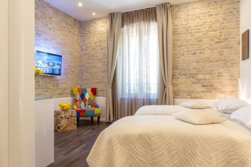 a bedroom with two beds and a brick wall at Pellegrini Luxury Rooms in Split