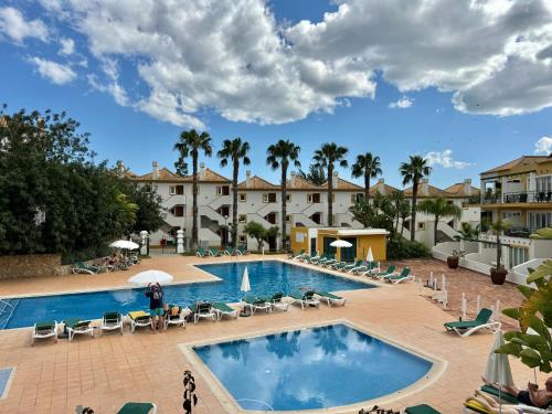 une piscine dans un complexe hôtelier avec des chaises et des palmiers dans l'établissement Grupo Morgado - Quinta do Morgado - Morgado Luxury, à Tavira