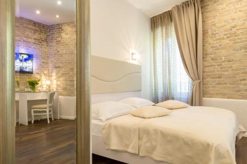 a bedroom with a bed and a table and a brick wall at Pellegrini Luxury Rooms in Split