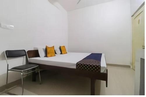 ein Bett mit bunten Kissen und einem Stuhl in einem Zimmer in der Unterkunft Mc B&B Hostel Ropar in Rūpnagar