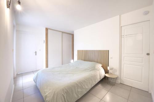 une chambre blanche avec un lit et une table dans l'établissement Le Cocon - Terrasse & BBQ - Centre historique Gare et Arènes à Proximité - Emplacement Idéal, à Arles