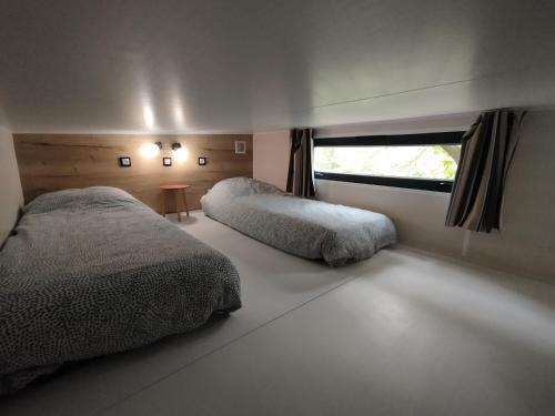 une chambre avec deux lits et une fenêtre dans l'établissement Tiny house bord de rivière, à Beaumont