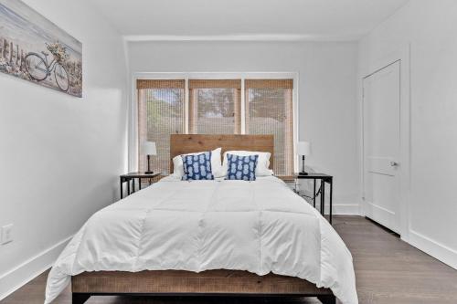 a white bedroom with a large bed with blue pillows at Splendid Mediterranean Retreat Gorgeous Outdoor in North Miami