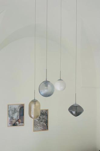 a group of lights hanging from a white wall at Nina Mia in Fasano