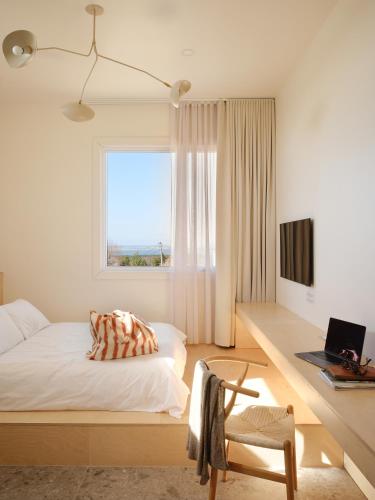 a bedroom with a bed and a window and a chair at Petit hôtel de la Montagne in Havre-Aubert