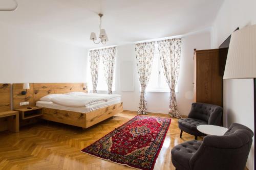 a bedroom with a bed and two chairs and a rug at KIRCHENWIRT an der Weinstrasse - Boutique Hotel in Ehrenhausen