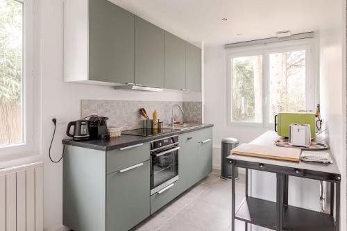 une cuisine avec des armoires blanches et un comptoir dans l'établissement Maison Mayel - Havre de Paix Chic & Nature à 30 min de Paris, à Lamorlaye