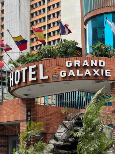 a hotel sign in front of a building with flags at Hotel Grand Galaxie in Caracas