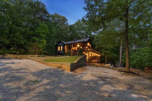 a house in the woods with lights on at Mins To Highlands Hot Tub, Fire Pit, Game Room in Franklin
