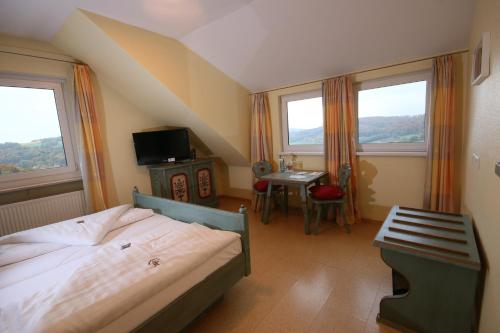 a bedroom with a bed and a desk and two windows at Berggasthof Hotel Igelwirt in Schnaittach