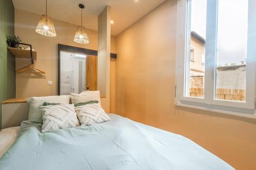 un grand lit dans une chambre avec une fenêtre dans l'établissement Magnifique appartement TERRASSE et PARKING privé place Dupuy, à Toulouse