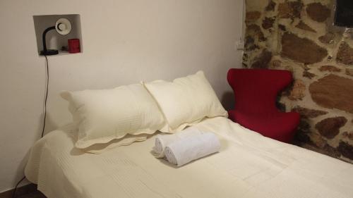 1 dormitorio con cama blanca y silla roja en La Posada de Juancho, en Junín