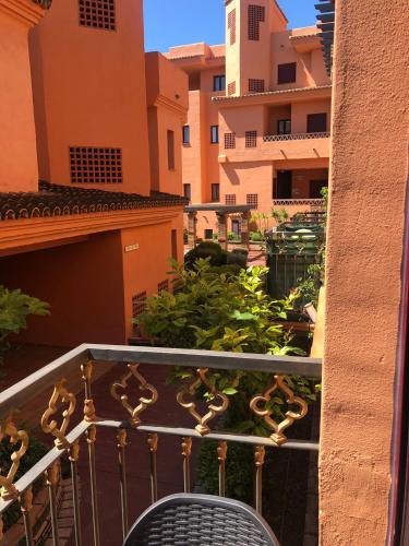 a balcony with a chair and some plants and buildings at Deluxe 2 bedroom Golf Apartment Puerto Banus Marbella 12 Minutes Away by G00gIeMaps in Estepona