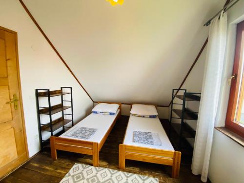 a room with two beds in a room with a window at Caloroczne Domki Aleksander in Kacwin