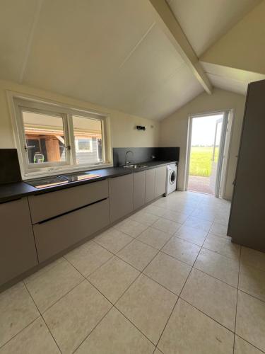 a large kitchen with a sink and a window at Vakantiehuis Weids uitzicht nabij Tjeukemeer in Rohel