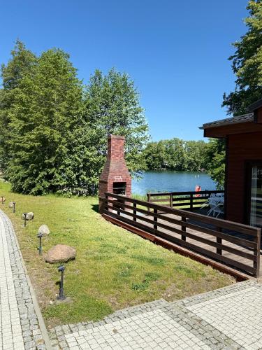 a wooden fence next to a lake and a building at Domek nad jeziorem Łagów - Mundi, Lake Park in Łagów