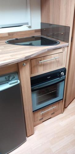 a kitchen with a stove and a counter top at Cosy Caravan in Scenic Snowdonia in Cwm-y-glo
