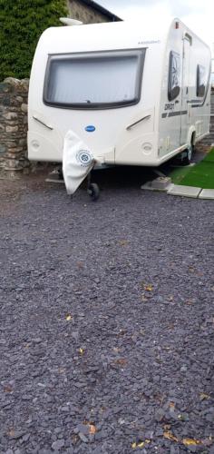 a white trailer parked in a parking lot at Cosy Caravan in Scenic Snowdonia in Cwm-y-glo