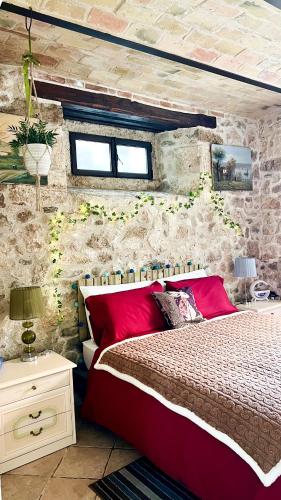 a bedroom with a red bed and a stone wall at Giardino sul Fiume a 10 min da Piazza del Popolo con parcheggio privato e giardino vista fiume in Ascoli Piceno