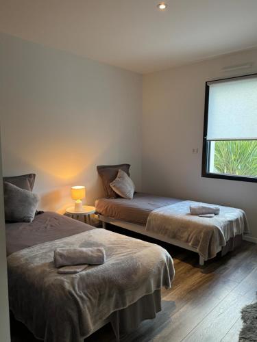 deux lits dans une chambre avec une fenêtre dans l'établissement L'Olivier de munet, à Distré